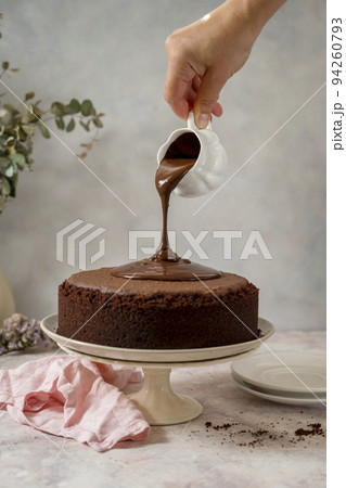 Chocolate cake. Pouring chocolate glaze on cake. Homemade chocolate cake on cake stand, home baking concept Chocolate cake. Pouring chocolate glaze on cake. Homemade chocolate cake on cake stand, home baking concept 94260793