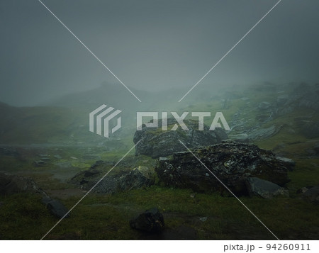 Big mountain rocks and boulders seen through the dense mist. Moody hiking scene with rainy weather Big mountain rocks and boulders seen through the dense mist. Moody hiking scene with rainy weather 94260911