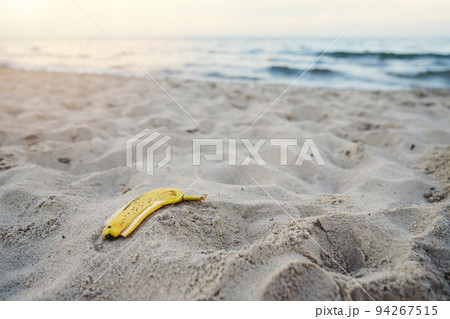 banana peel lying on the sand beach. beach pollution 94267515