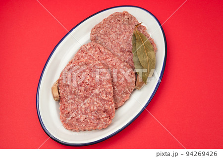 fresh raw minced meat on white dish with bay leaf 94269426