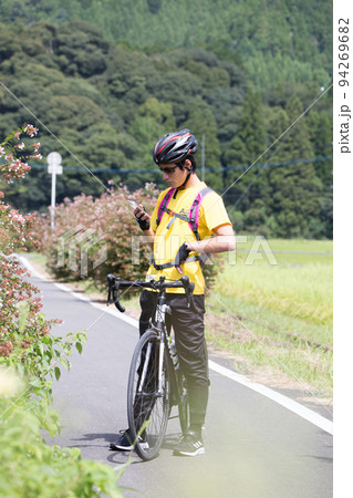 サイクリングの途中で立ち止まってスマホを見ている男性 94269682