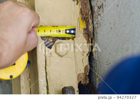 young master repairing old garage doors. handyman repairing a rotten wooden building. 94270327
