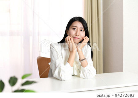 屋内で頬杖をつく若い女性 94272692