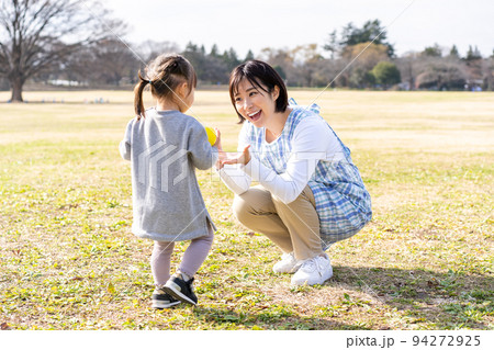 公園の芝生広場で遊ぶ園児と保育士 94272925