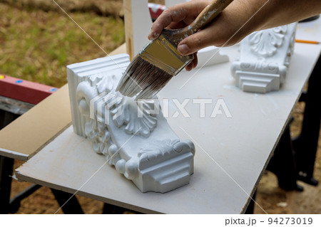 Painting wooden corbels for the kitchen island with worker is using paintbrush Painting wooden corbels for the kitchen island with worker is using paintbrush 94273019