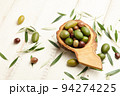 Mixed olives in wooden bowl on white planks background 94274225