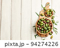 Mixed olives in wooden bowl on white planks background 94274226