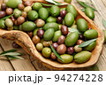 Mixed olives in wooden dish on planks background 94274228