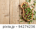 Mixed olives in wooden dish on planks background 94274236