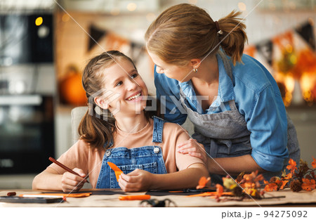 Happy smiling family mother and daughter making Halloween home decorations together Happy smiling family mother and daughter making Halloween home decorations together 94275092