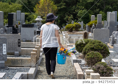 お墓参りに来てお墓の掃除をしているシニア女性の後ろ姿 お墓参りに来てお墓の掃除をしているシニア女性の後ろ姿 94275453