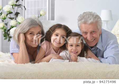 Grandparents and grandchildren lie on the bed Grandparents and grandchildren lie on the bed 94275496