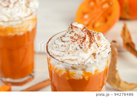 Pumpkin latte with whipped cream on light wooden background. Hot spicy smoothie. Vegetable vegan drink. 94276486