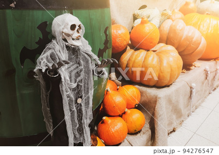 Halloween decorations. Skeleton and fresh pumpkins. Farmers market. Ripe vegetables on shelves for sale in countryside. 94276547