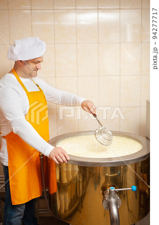 man makes cheese, boils milk in cistern, heating, temperature. Milk folding process, home production, business, individual entrepreneur. tile man makes cheese, boils milk in cistern, heating, temperature. Milk folding process, home production, business, individual entrepreneur. tile 94277717