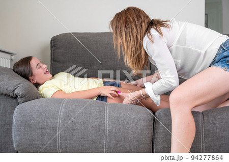 Loving mother tickling her little daughter on the sofa at home Loving mother tickling her little daughter on the sofa at home 94277864