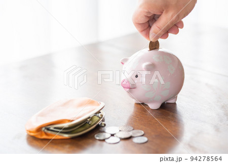ブタの貯金箱に10円硬貨を入れる男性の手元 94278564