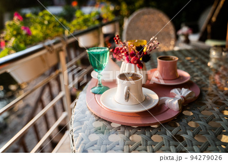 Turkish coffee cups served outside with water flowers and delight dessert in romantic setup on glass table 94279026