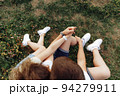 A guy and a girl after a long walk in nature sat down to rest in a glade. Around them are green grass and wildflowers.They hold each other's hands. 94279911