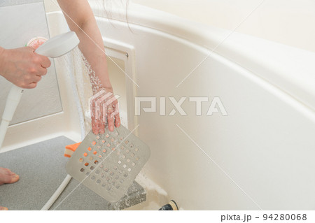 【風呂掃除をするミドル主婦　排水口の蓋をシャワーで流す】 94280068