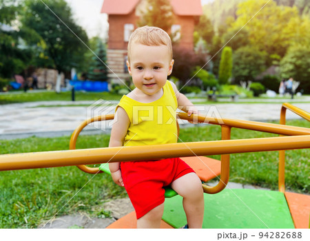 Happy toddler boy rides on a swing. Indoor playground. A cute boy of one and a half years. Selective focus Happy toddler boy rides on a swing. Indoor playground. A cute boy of one and a half years. Selective focus 94282688