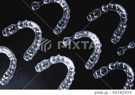 a pattern of invisible plastic aligners lie on a black background a pattern of invisible plastic aligners lie on a black background 94282934