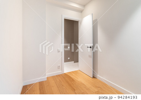 Empty room with laminate flooring and newly painted white walls. Repair and construction concept. Empty room with laminate flooring and newly painted white walls. Repair and construction concept. 94284193