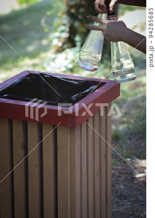 In the hands of two empty glass bottles with a bucket. Ejection of container glass In the hands of two empty glass bottles with a bucket. Ejection of container glass 94285685