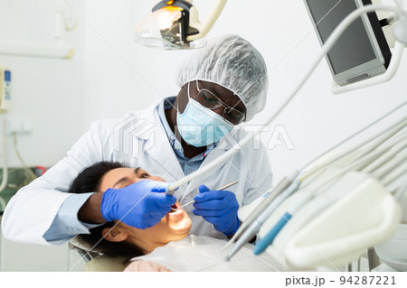Orthodontist using tools and curing toothache of asian woman 94287221