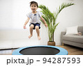 トランポリンでジャンプして遊ぶ2歳の女の子 94287593