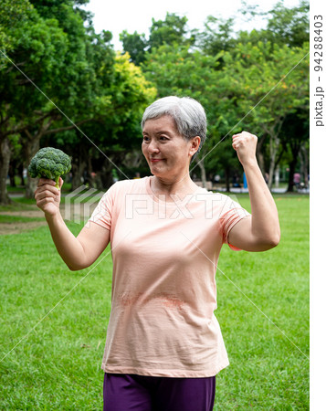 Portrait of happy senior adult elderly asia woman smiling standing and holding fresh vegetable in the park. Portrait of happy senior adult elderly asia woman smiling standing and holding fresh vegetable in the park. 94288403