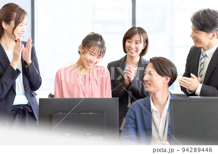 照れ笑いを浮かべる若い社員と、彼女を褒める中堅やベテランの社員 照れ笑いを浮かべる若い社員と、彼女を褒める中堅やベテランの社員 94289446