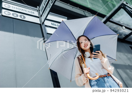 Beautiful Asian woman happiness holding umbrella and listening favourite music on headphones from mobile phone, Happiness relaxation summer in park with music 94293021
