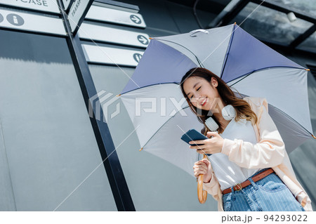 Beautiful Asian woman happiness holding umbrella and listening favourite music on headphones from mobile phone, Happiness relaxation summer in park with music 94293022
