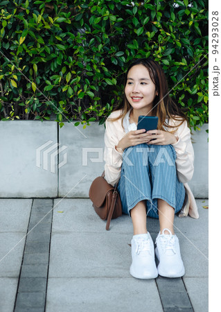 Beautiful Asian woman listening favourite music on headphones from mobile phone, Happiness relaxation summer in park with music riding bicycle in green park. 94293028