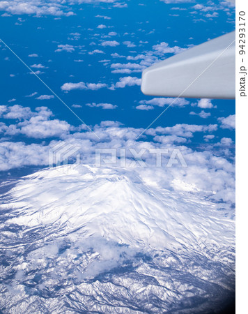 飛行機から見た雲の上に浮かぶ冠雪の鳥海山 94293170