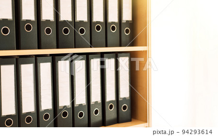 Black office folders standing on cabinet shelves 94293614