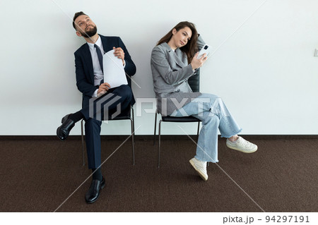 office employees sit on chairs man and woman waiting for an interview office employees sit on chairs man and woman waiting for an interview 94297191