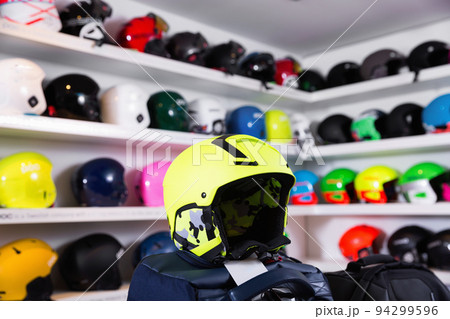 Yellow skiing helmet on background with colorful ski headwear on shelves 94299596