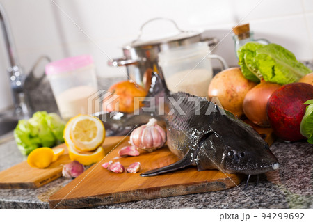 Uncooked raw sturgeon at plate near vegetable on table 94299692