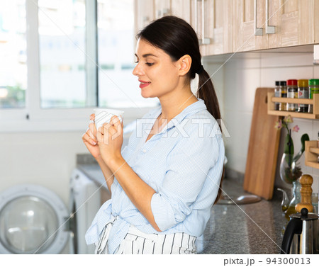 Portrait of happy brunette woman in kitchen 94300013
