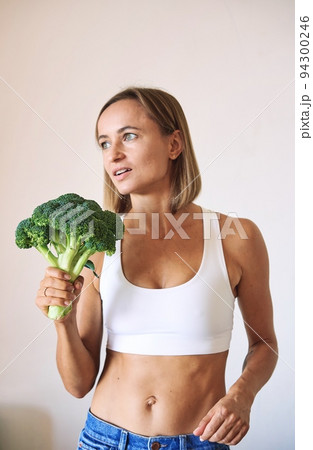 young woman dressed in white t-shirt showing with broccoli 94300246