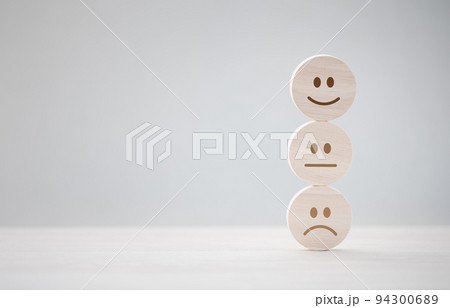 closeup happy emotion face on wooden piece with unhappy one behind for satisfaction survey 94300689