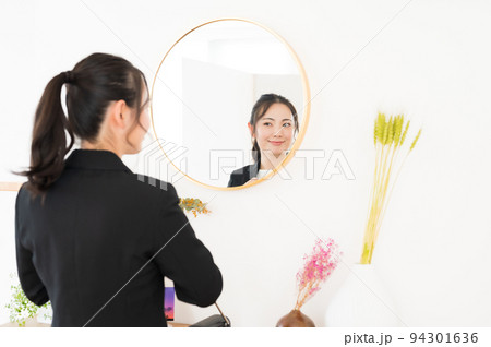 鏡の前で身だしなみのチェックをする女性 鏡の前で身だしなみのチェックをする女性 94301636
