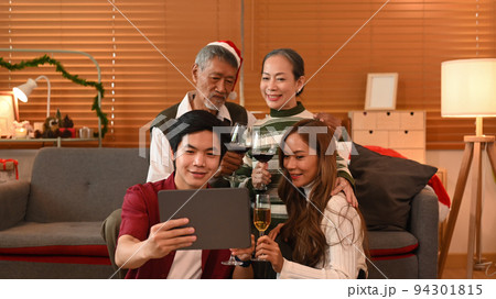 Happy family making video call over digital tablet, sitting in room decorated for celebrating New year and Christmas festive 94301815
