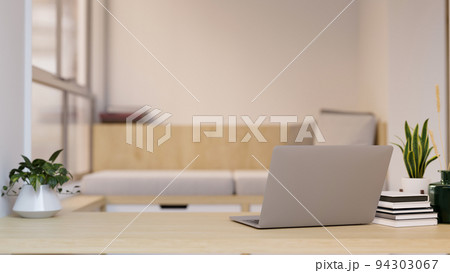 Workspace with laptop and copy space on wood tabletop over blurred minimal living room Workspace with laptop and copy space on wood tabletop over blurred minimal living room 94303067