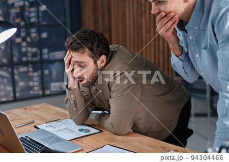 two tired employees working with financial documents until late at night . two tired employees working with financial documents until late at night . 94304466