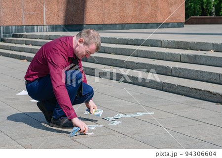 Businessman dropped a lot of money on the ground and picks it up 94306604