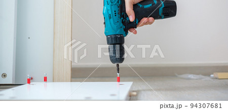 man using a cordless screwdriver assembling furniture at home, Carpenter working with electric screwdriver on the work man using a cordless screwdriver assembling furniture at home, Carpenter working with electric screwdriver on the work 94307681