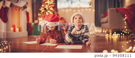 Children lying on the floor indoors and writing letters for Santa Claus. Children lying on the floor indoors and writing letters for Santa Claus. 94308111